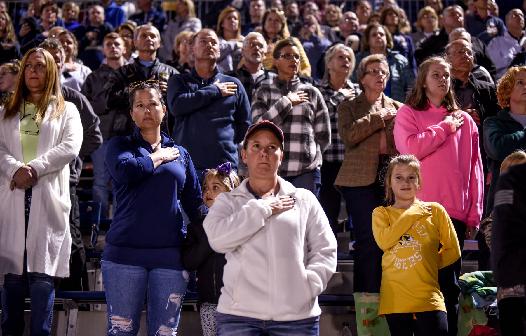 The crowd places their hands over their hearts for the pledge of allegiance